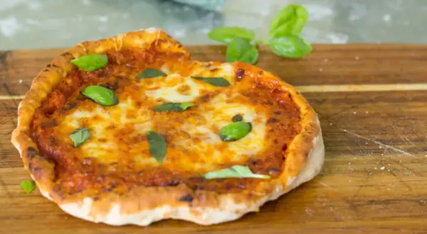 En perfekt pizza i airfryer, med smält ost och färsk basilika, serverad på en träskärbräda.