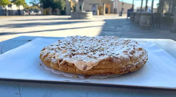 Tarte aux pignons de Gruissan, saupoudrée de sucre glace, sur une table ensoleillée.