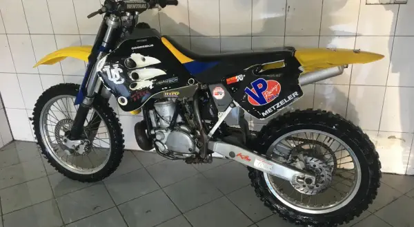 Husqvarna WR 250, gotowy do akcji. Czarne plastiki z żółtymi i niebieskimi akcentami, opony Metzeler.