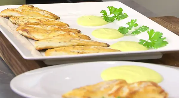 Pescado dorado a la plancha con salsa cremosa y perejil fresco. Un plato ligero y sabroso.