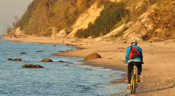 Rowerzysta na plaży, cieszący się piękną, jesienną pogodą na nadmorskiej trasie rowerowej Trójmiasto.