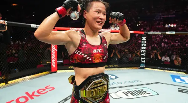 UFC strawweight champion celebrates victory, flexing her muscles and holding a drink can.