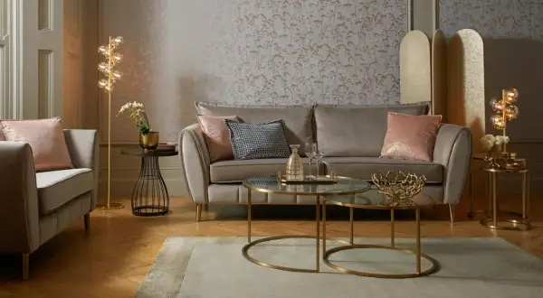 Przytulny salon glamour z szarą sofą, różowymi poduszkami i złotymi dodatkami.