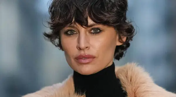 Ein modischer Pixie Cut mit feinem Haar betont die grünen Augen einer Frau in einem Pelzmantel.