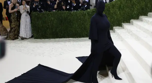 Kim Kardashian al Met Gala, un'apparizione misteriosa in nero totale, con un abito che si estende sul tappeto bianco.