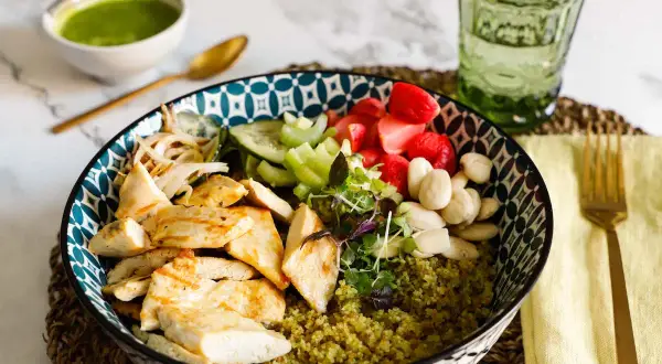 Una ciotola colorata con pollo grigliato, verdure fresche, fragole e mandorle su un letto di cous cous. Perfetta per le tue ricette con il cous cous.