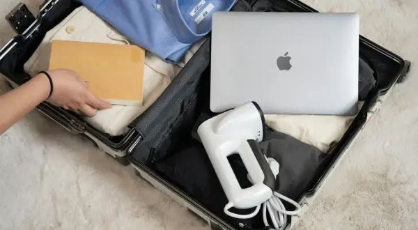 Pakowanie bagażu rejestrowanego: laptop, koszula, książka i podręczny parownica.