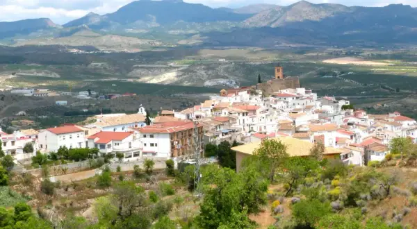 Vista panorámica de las menas Almería, un pueblo blanco en una ladera con montañas al fondo.