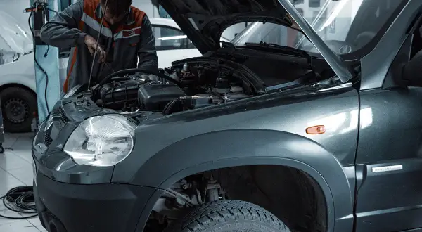 Mechanik wymienia żarówkę w przednim reflektorze Skody Fabii 3.