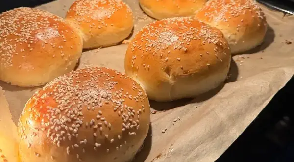 Świeżo upieczone, złociste bułki do burgerów posypane sezamem, gotowe do przygotowania pysznego posiłku.