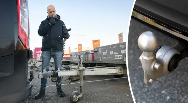 Man kontrollerar kopplingen till en släpvagn, kanske för att säkerställa att fordons totalvikt inte överskrids.