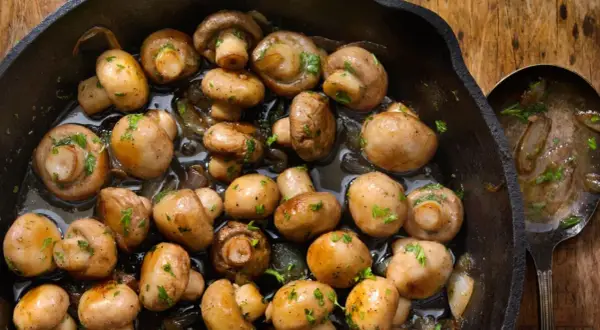 Champiñones salteados en sartén de hierro fundido, perfectos para tus recetas con champiñones. Un plato sencillo y delicioso.