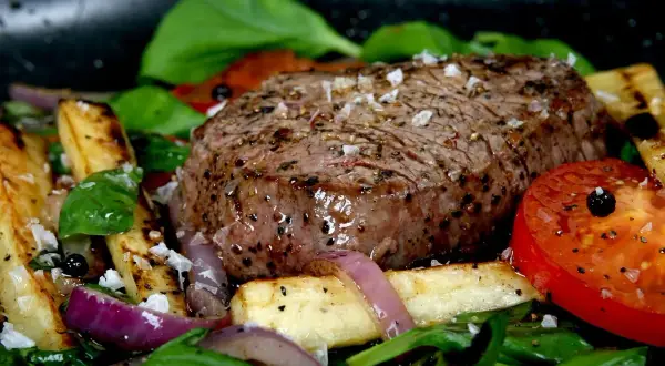 Soczysty stek z polędwicy, posypany grubą, swańską solą, podany z pieczonymi ziemniakami, pomidorem i rukolą.