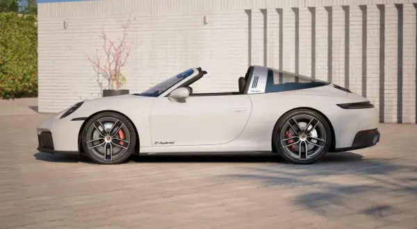 Białe Porsche 911 Targa z otwieranym dachem, z napisem "Targa" na błyszczącym pałąku, stoi na brukowanym podjeździe.