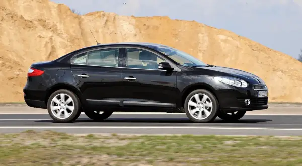 Czarny Renault Fluence jedzie po drodze, w tle piaszczyste wzgórza.
