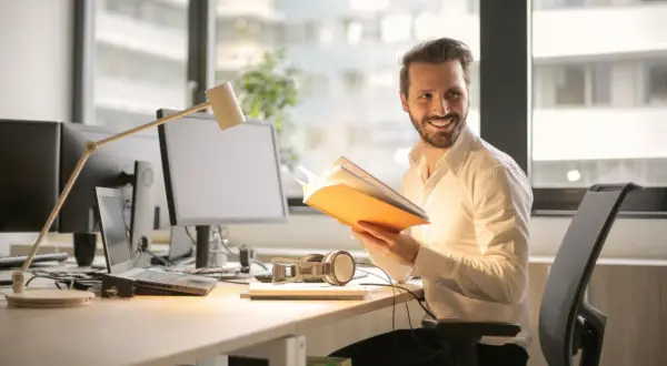 Ein Mann im Büro liest ein Buch. BWL: Was macht man da? Er lernt, wie man erfolgreich ist.
