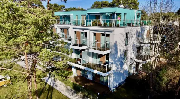 Nowoczesne władysławowo apartamenty przy plaży z widokiem na morze. Balkony z przeszklonymi balustradami i zielone otoczenie.