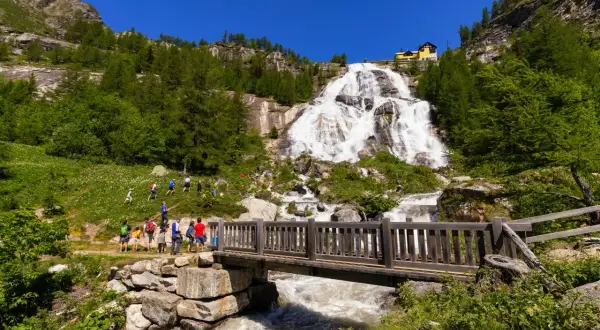 Cascata imponente, un ponte di legno e un sentiero con escursionisti: ecco cosa vedere in Piemonte per un'avventura nella natura.