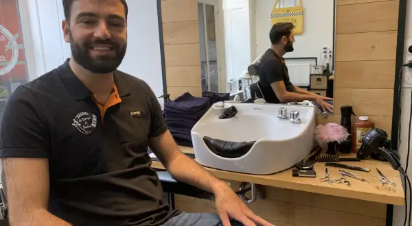 Le tonsor souriant, barbier dans son salon, entouré de ses outils de coiffure.