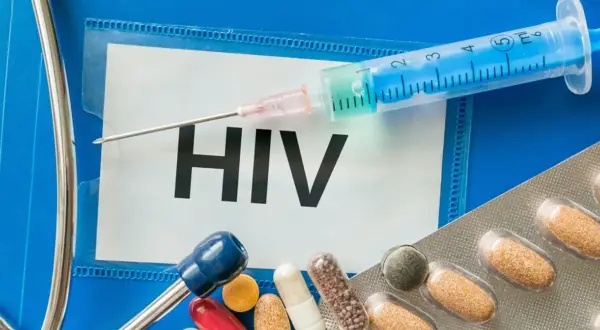 Strzykawka, tabletki i stetoskop na tle napisu HIV.