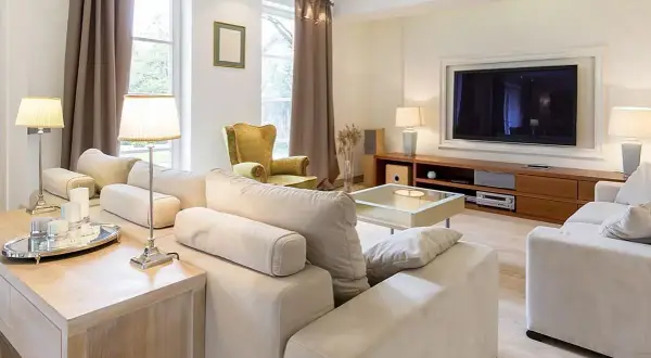 Przytulny pokój 20m2 z wygodną kanapą, fotelem i telewizorem. Jasne kolory i eleganckie dodatki tworzą relaksującą atmosferę.