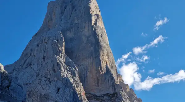 El imponente Urriellu se alza majestuoso bajo un cielo azul, invitando a contemplar el tiempo y la grandeza de la montaña.