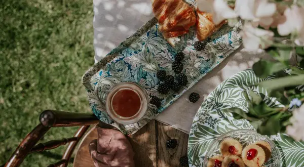 En härlig sommar fika med croissanter, björnbär och småkakor på ett vackert mönstrat fat.