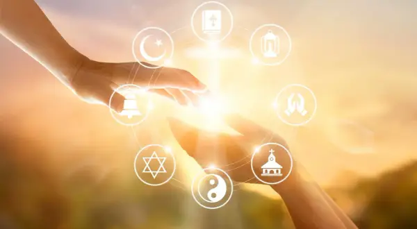 Dłonie łączą się, otoczone symbolami różnych religii, odzwierciedlając jedność i poszukiwanie duchowości, która jest starsza niż najstarsza religia świata.