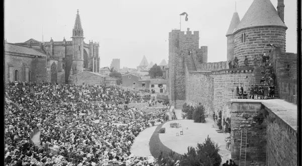 Vue d'un spectacle dans les arènes de Carcassonne, avec une foule nombreuse assise et la cité médiévale en arrière-plan.