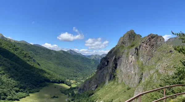 Un valle verde y montañoso con un arco natural en la roca, ideal para rutas circulares en Somiedo.