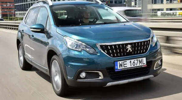 Turkusowy Peugeot 2008 na drodze. Kierowca w środku. Wiele pozytywnych peugeot 2008 opinie o tym modelu.