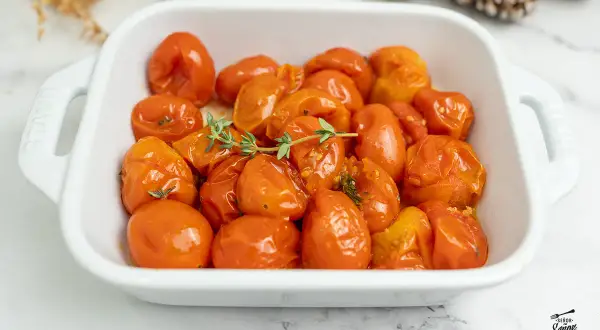 Tomates confitados en una fuente blanca, con ramitas de tomillo fresco. Un plato delicioso y aromático.