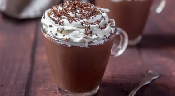 Cioccolata calda con acqua e cacao, guarnita con panna montata e codette di cioccolato. Un comfort food perfetto per riscaldarsi.