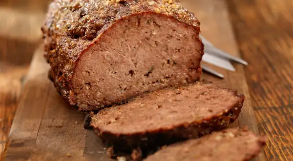 Un delizioso polpettone al forno, tagliato a fette su un tagliere di legno, pronto per essere gustato.