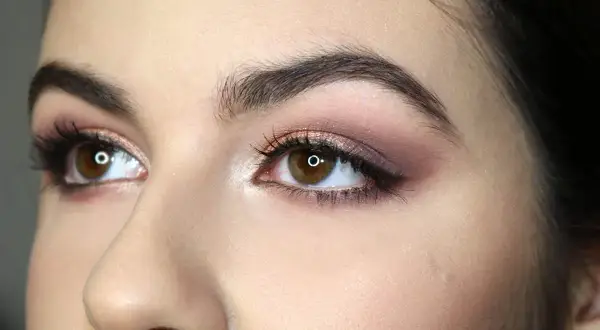 Occhi marroni con ombretto rosa e marrone, ciglia lunghe e eyeliner. Un esempio di come truccare gli occhi per un look sofisticato.