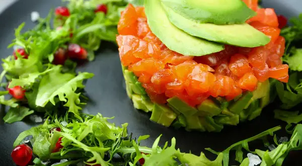 Tartare di salmone e avocado, guarnita con melagrana e insalatina fresca. Antipasti sfiziosi per stupire con gusto e colore.
