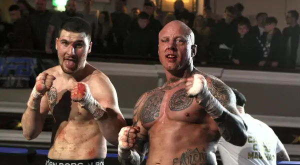 Två blodiga kämpar redo för bare knuckle boxing Sverige. Publiken hejar på i bakgrunden.
