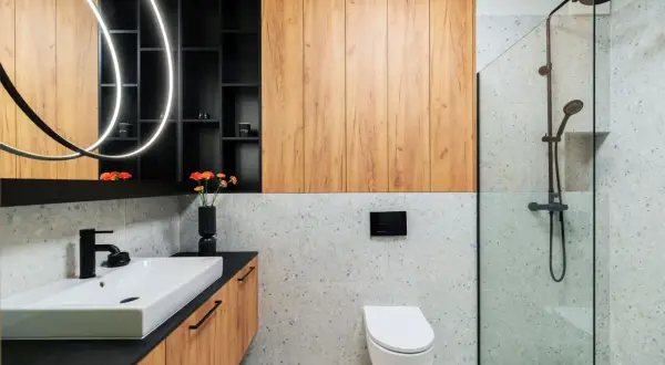 Nowoczesna łazienka inspiracje: drewniane panele, kamień terrazzo, czarna armatura i designerskie oświetlenie tworzą stylową przestrzeń.
