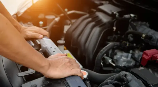 Man checks the engine of a used car, ensuring it's in good condition before purchase.