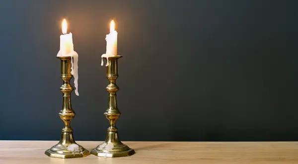 Zwei brennende Kerzen auf Messing-Leuchtern, die die Bedeutung des 45. Hochzeitstages symbolisieren: ein langes, gemeinsames Leben.