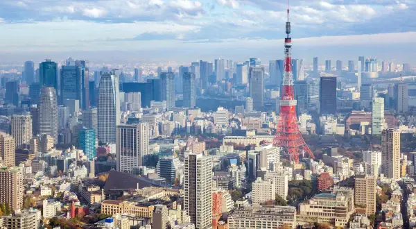 Rozległy krajobraz tokio miasto z wieżą Tokyo Tower na pierwszym planie i licznymi drapaczami chmur w tle.