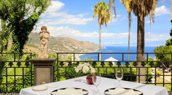 Tavola apparecchiata con vista mare a Taormina, un'esperienza tra i migliori ristoranti.