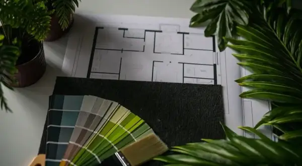 Floor plan, paint swatches, and a brush lay on a surface, ready for your next remodel.