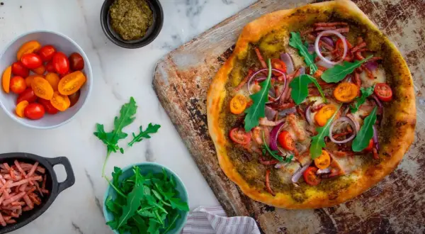 En läcker pizza bianco med parmaskinka, ruccola, körsbärstomater och rödlök. Perfekt för en mysig kväll!