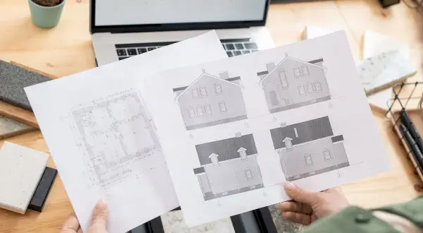 Ręce trzymające plany architektoniczne domu i rzuty.