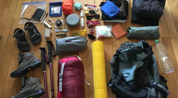 Préparation du contenu sac rando 3 jours : chaussures, sac de couchage, matelas, vêtements, gourde, kit de premiers secours, et autres essentiels.