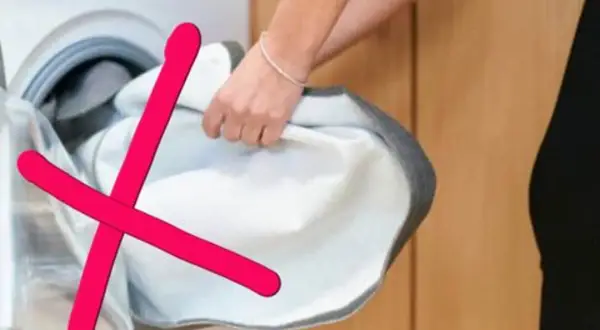 Rote Kreuze über einem weißen Wäschestück, das aus einer Waschmaschine genommen wird. Das zeigt, was darf nicht in den trockner.
