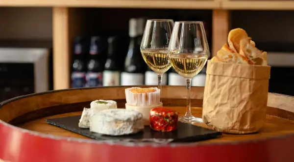 Dégustation de fromages et de pain frais avec deux verres de vin blanc, une scène parfaite pour un vin Paris.