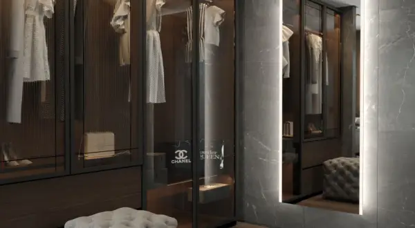 En spegel med belysning bakom spegel ger ett mjukt ljus i en lyxig walk-in-closet med kläder och accessoarer.
