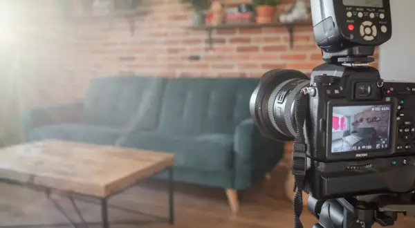 Aparat fotograficzny na statywie w salonie, gotowy do ujęć. W tle kanapa i ceglana ściana, tworzące atmosferę do trików z dymu.
